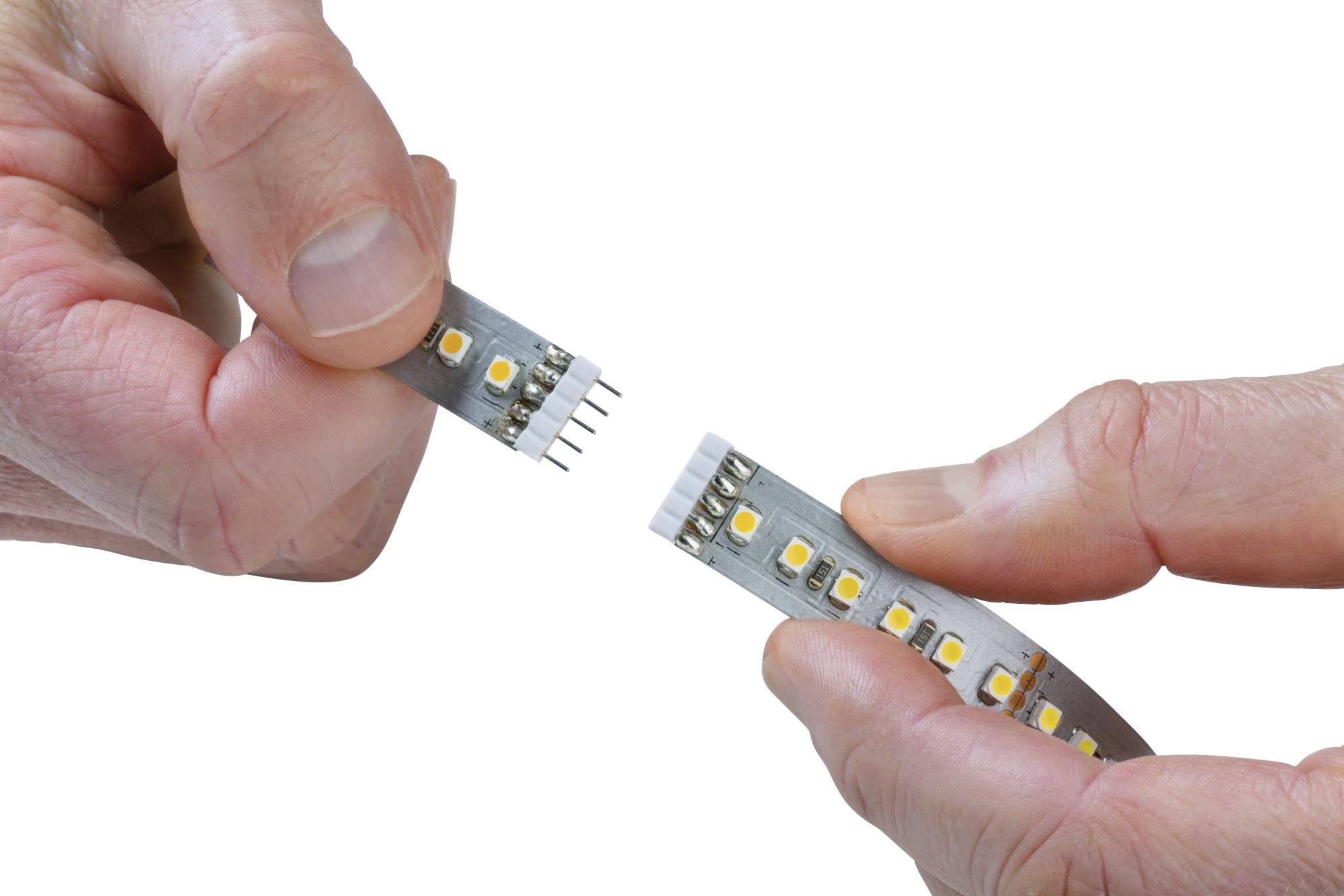 Dvě ruce spojují dva díly LED pásku s navzájem kompatibilními konektory, které vytvářejí elektrické propojení.
