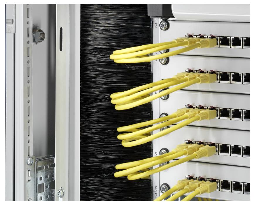 Síťový rack s několika žlutými ethernetovými kabely zapojenými do patch panelu ukazuje organizaci datových spojení.
