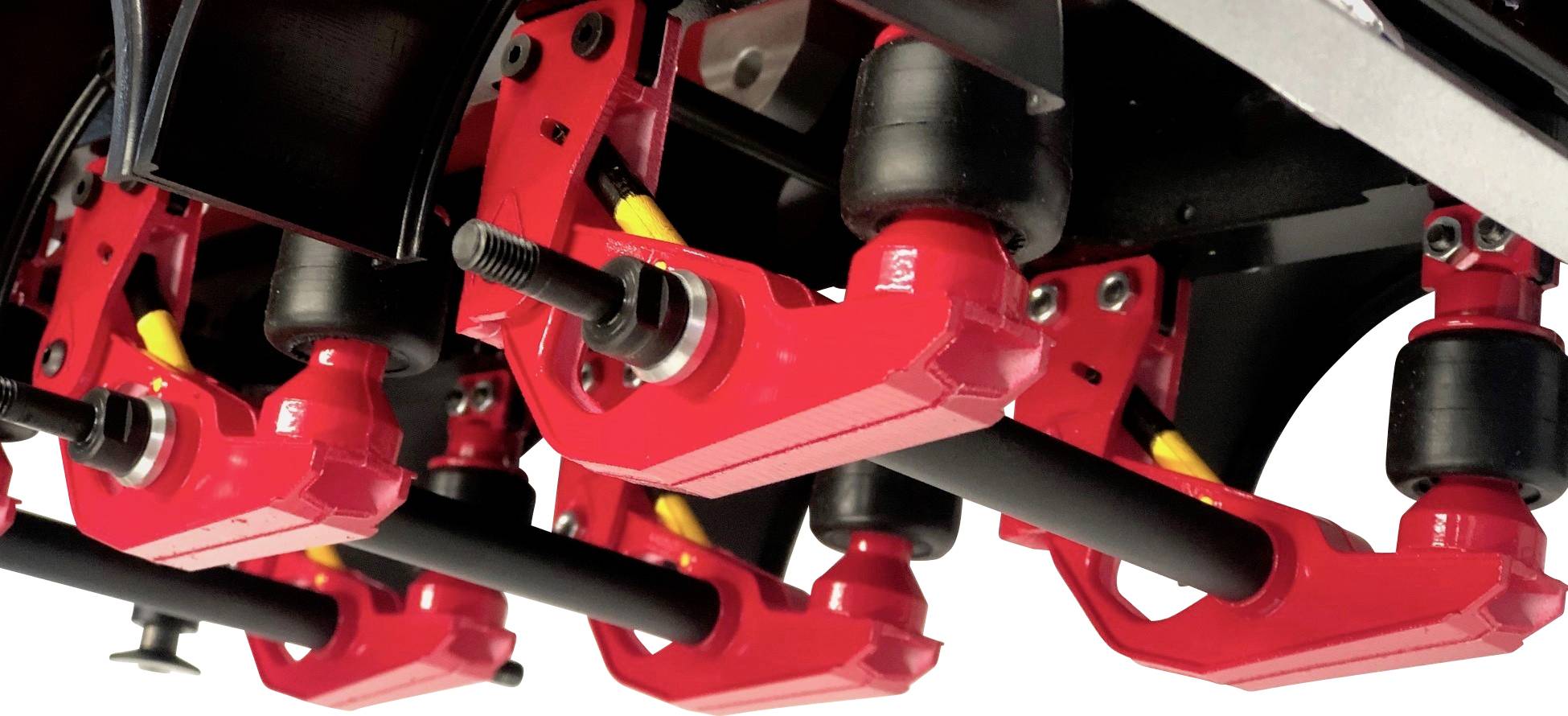 Detailní záběr červených mechanických komponent připevněných k černé struktuře. Obsahují žluté a černé kabely.