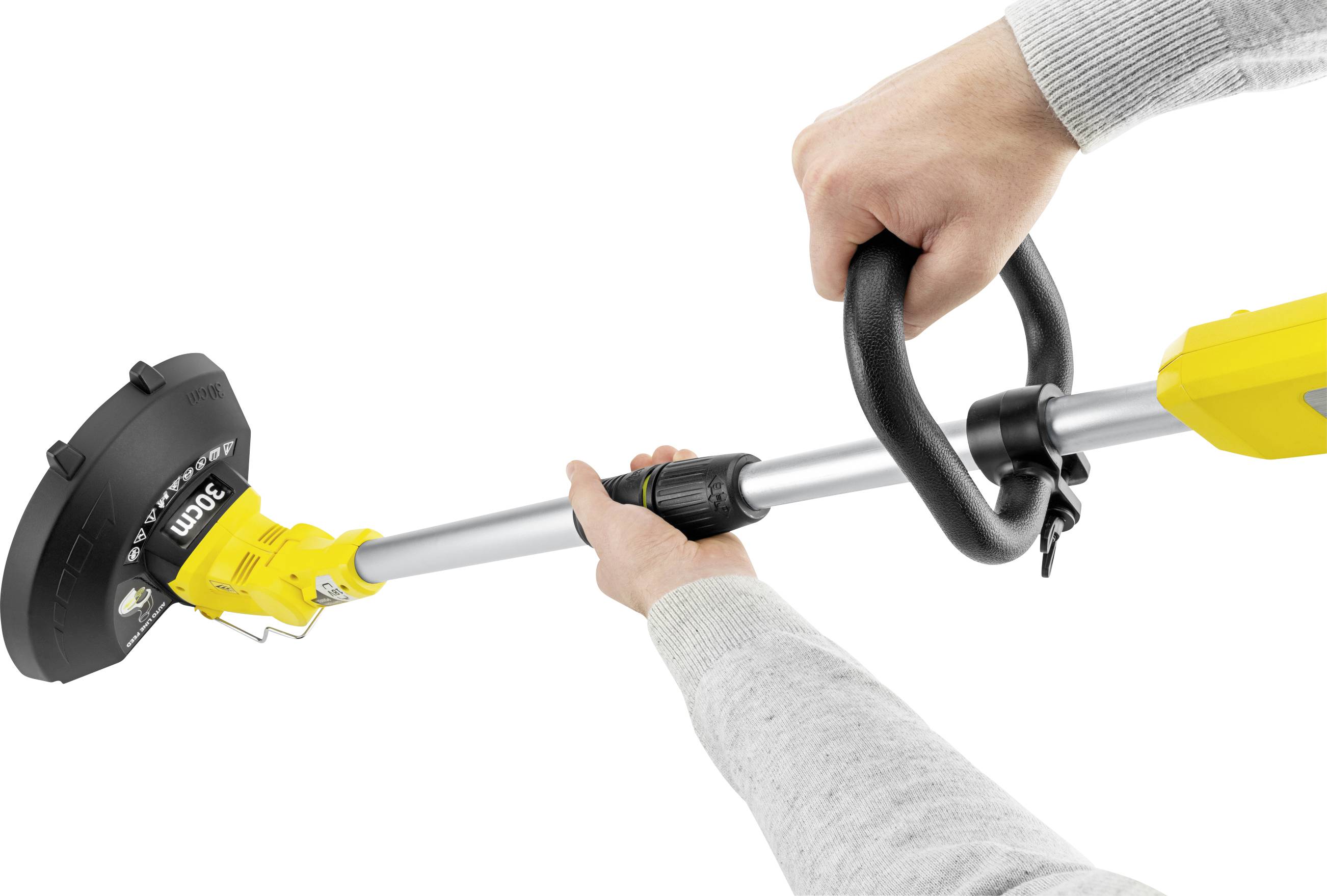 Detailní záběr elektrického zastřihovače s žlutými a černými prvky, držený dvěma rukama.