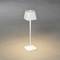 Moderní bílá stojací lampa se čtvercovým stínidlem svítí na šedé podlaze.