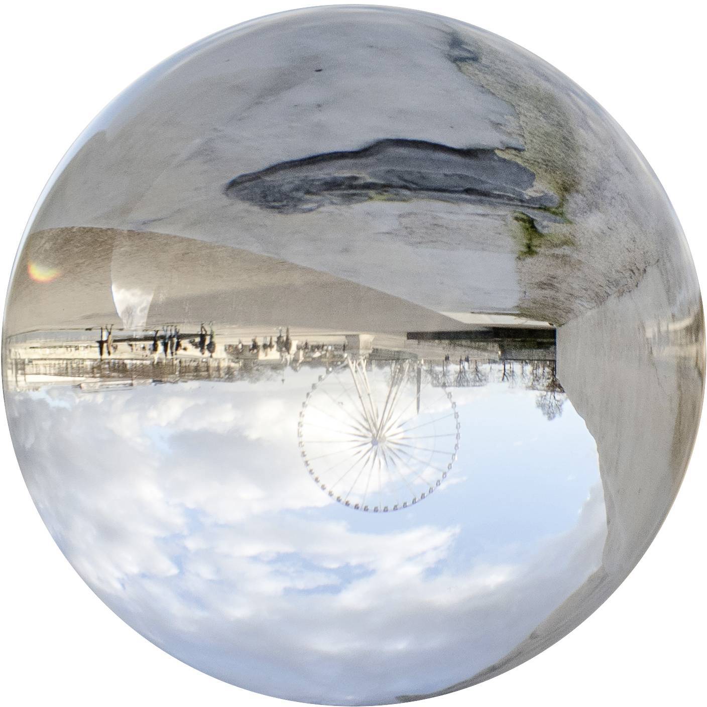 Vzhůru nohama pořízený snímek obřského kola, obloha s mraky a těžko rozeznatelná městská krajina v kulovité reflexi.