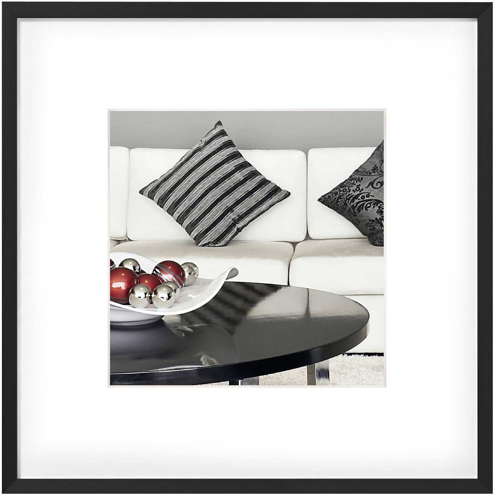 Moderní obývací pokoj s jasnou pohovkou, pruhovanými polštáři a kulatým tmavým stolem s dekorativními lesklými koulemi.