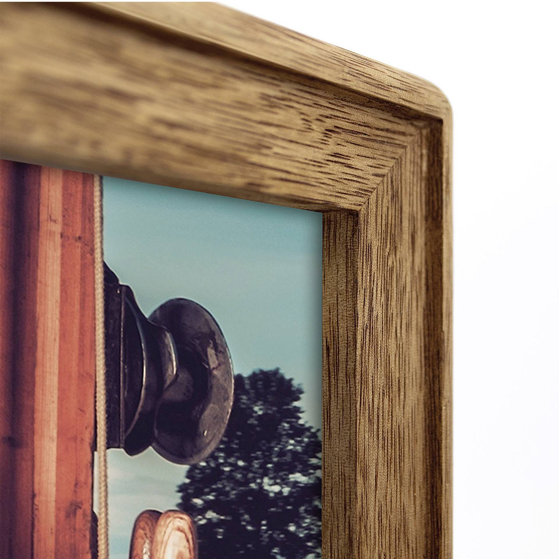 Dřevěný rámeček s výřezem fotografie v popředí. Na fotografii je vidět klika dveří a rozmazaný strom v pozadí.