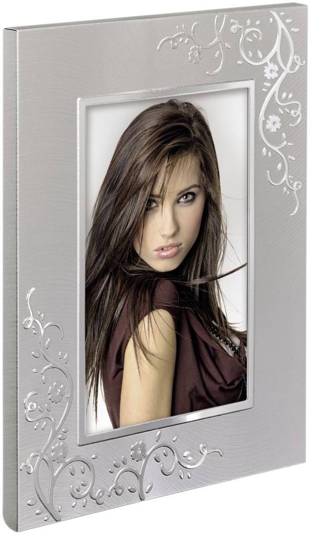Stříbrný fotorámeček s florálním vzorem zobrazuje fotografii ženy s dlouhými tmavými vlasy a hnědým horním dílem oblečení.