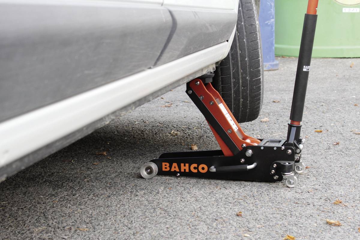 Detailní záběr automobilu zvedaného hydraulickým zvedákem.