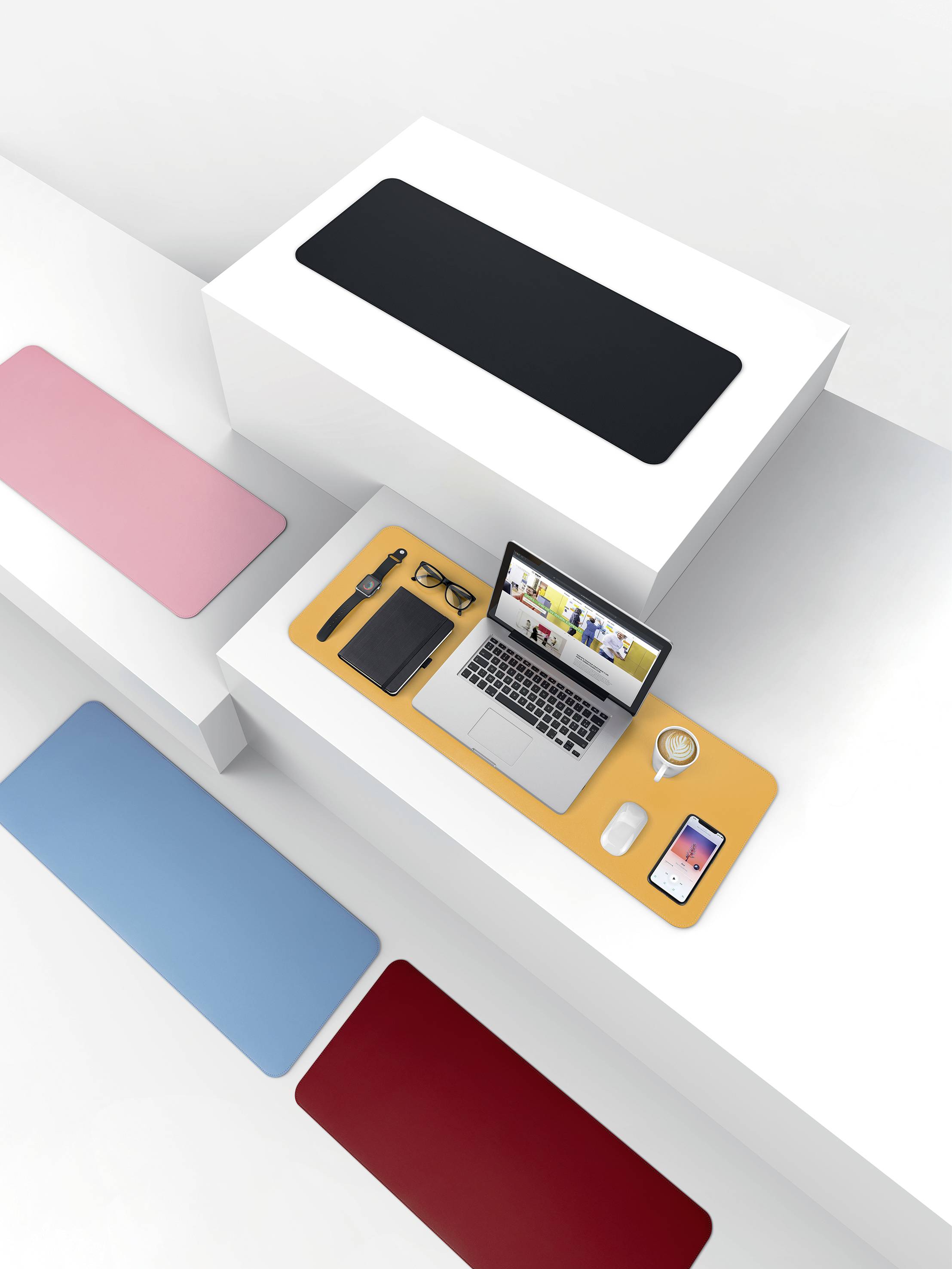 Laptop, brýle, šálek a dva smartphony na oranžové podložce pod počítač. Kolem pestré povrchy.