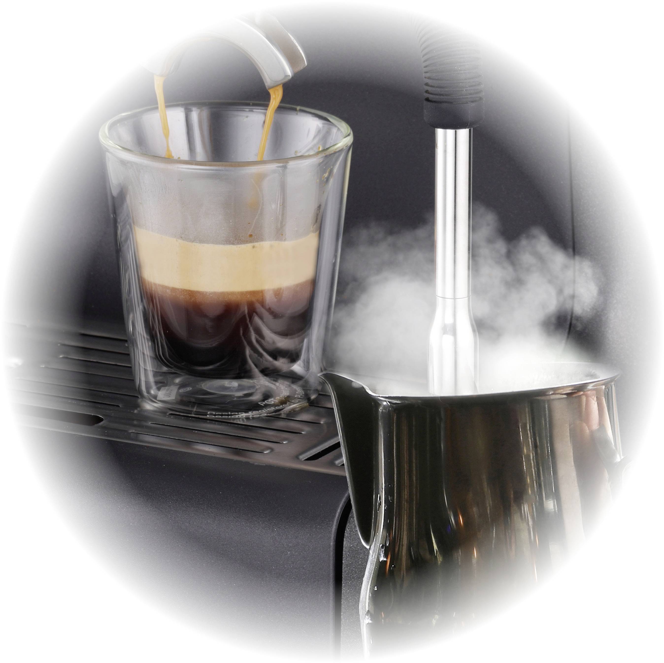 Sklenice čerstvě připravené espresso je nalévána, vedle ní se pare konvička s mlékem.