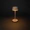 Moderní stolní lampa s jednoduchým, elegantním designem, která vyzařuje teplé světlo v tmavé místnosti.