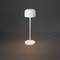 Moderní volně stojící bílá stojací lampa jemně osvětluje tmavé pozadí.