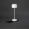 Moderní stolní lampa s jednoduchým bílým designem na tmavě šedém pozadí. Lampa má kulatý, minimalistický vzhled.