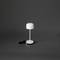 Malá, moderní stolní lampa s kulatým stínítkem a USB kabelem, na šedém pozadí.
