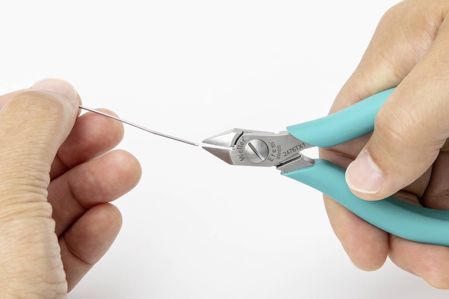 Osoba drží drát a pomocí modrých kleští jej stříhá.