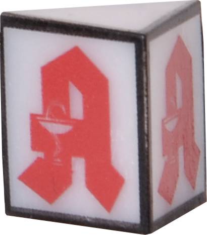 Kostka zobrazuje červené lékárenské logo na bílém pozadí, trojrozměrně znázorněné na každé straně.