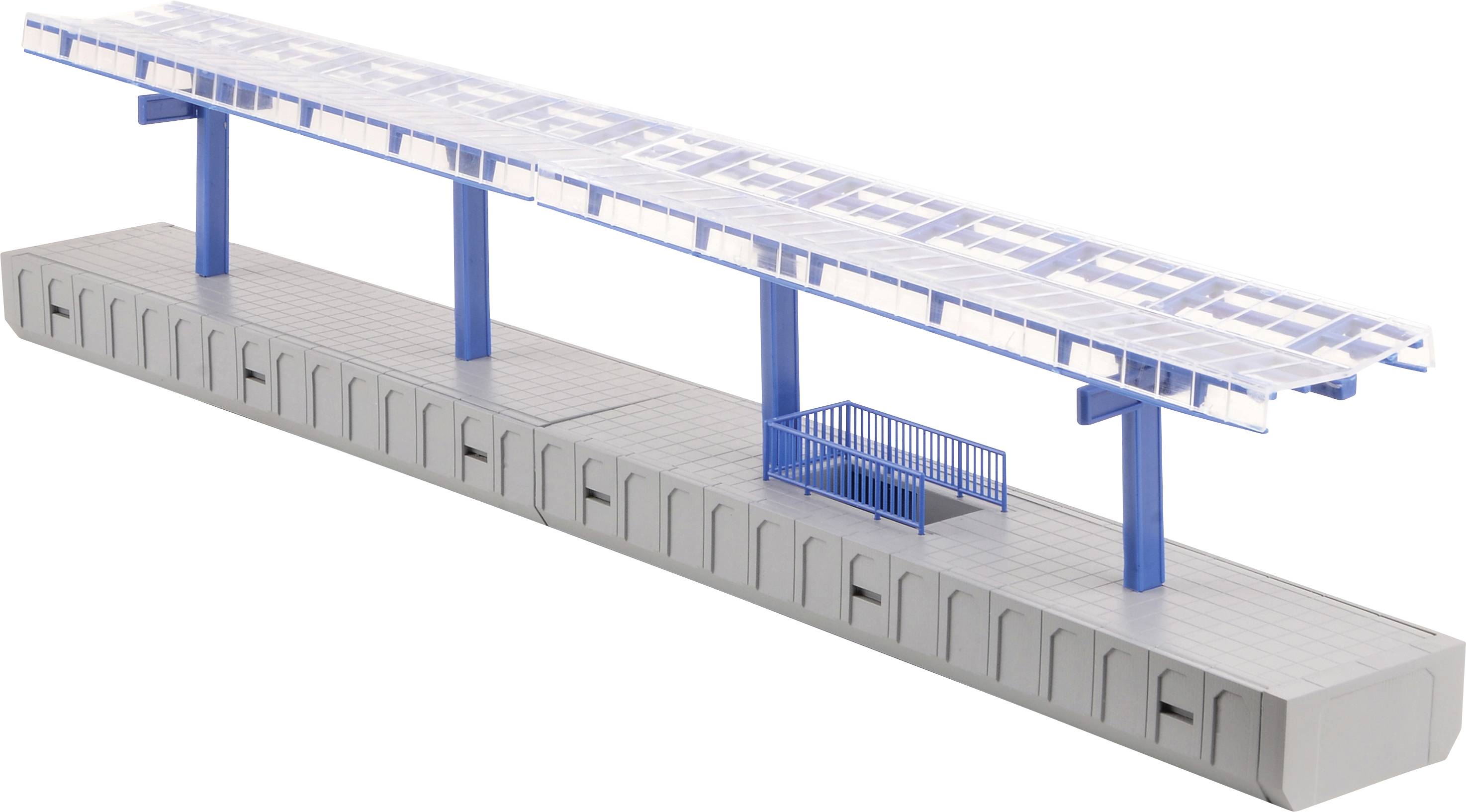 Modelové nádraží s modrou střechou, modrými sloupy a malým modrým schodištěm; simuluje moderní nástupní platformu.