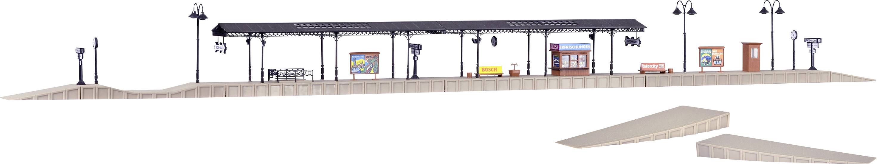 Miniaturní nástupní plocha s přístřeškem, lavičkami, reklamními plochami a pouličními lampami. Model železniční stanice s čekárnou.