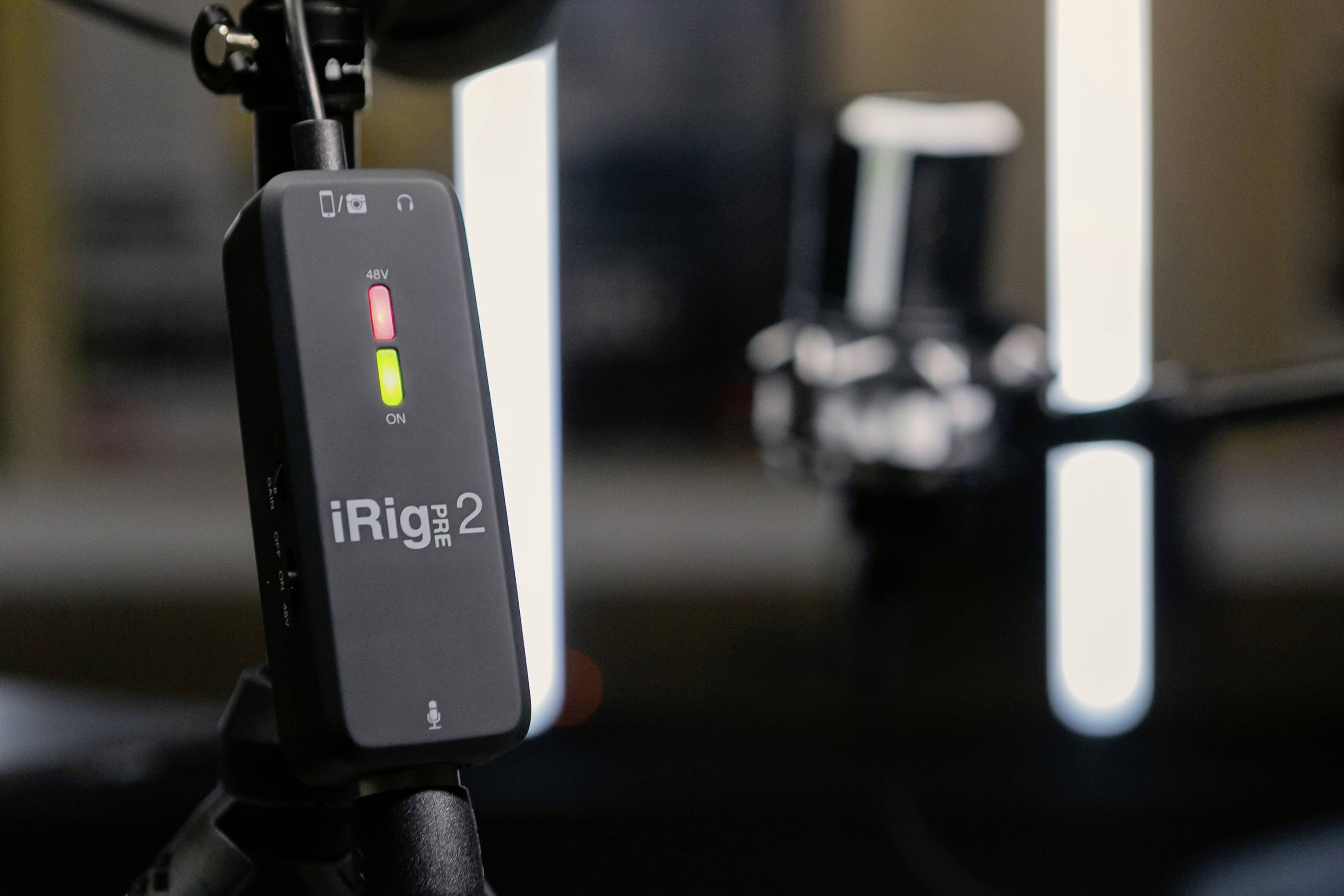 Mikrofon iRig Mic Studio s osvětleným zapínacím tlačítkem na mikrofonním stojanu ve studiu.