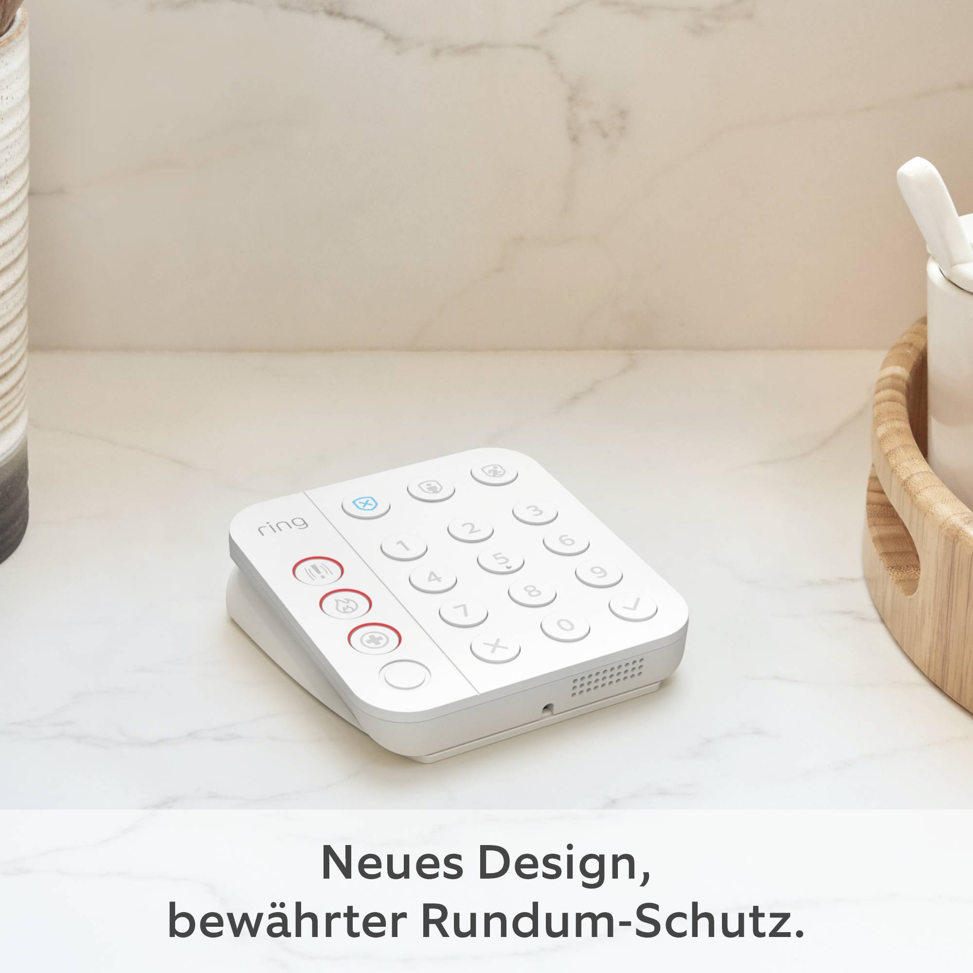 Bílý bezpečnostní systém s tlačítky leží na stole. Text pod ním: 'Nový design, osvědčená komplexní ochrana'.