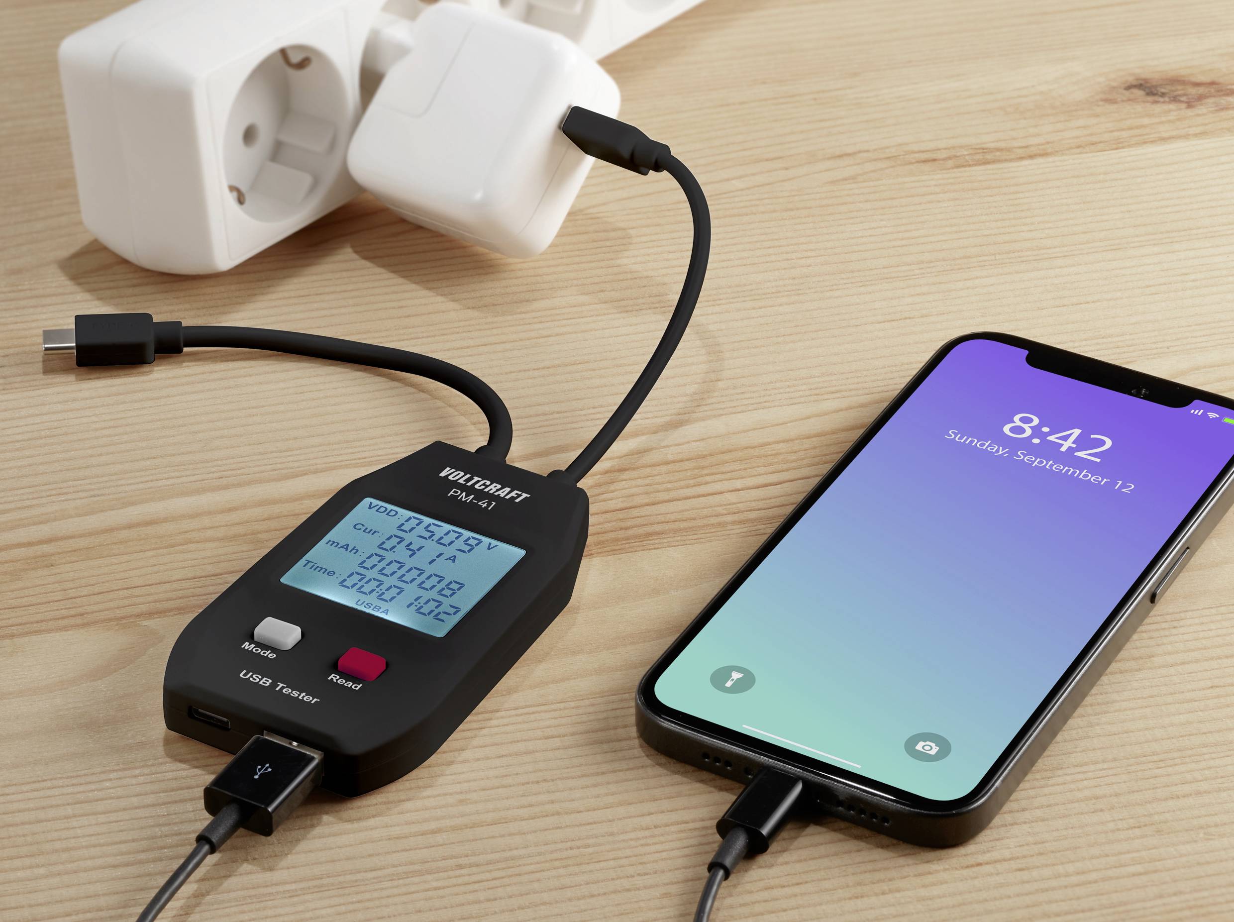 Mobilní telefon je nabíjen pomocí USB nabíjecího kabelu, připojeného k měřicímu přístroji, který zobrazuje napětí, proud a čas.