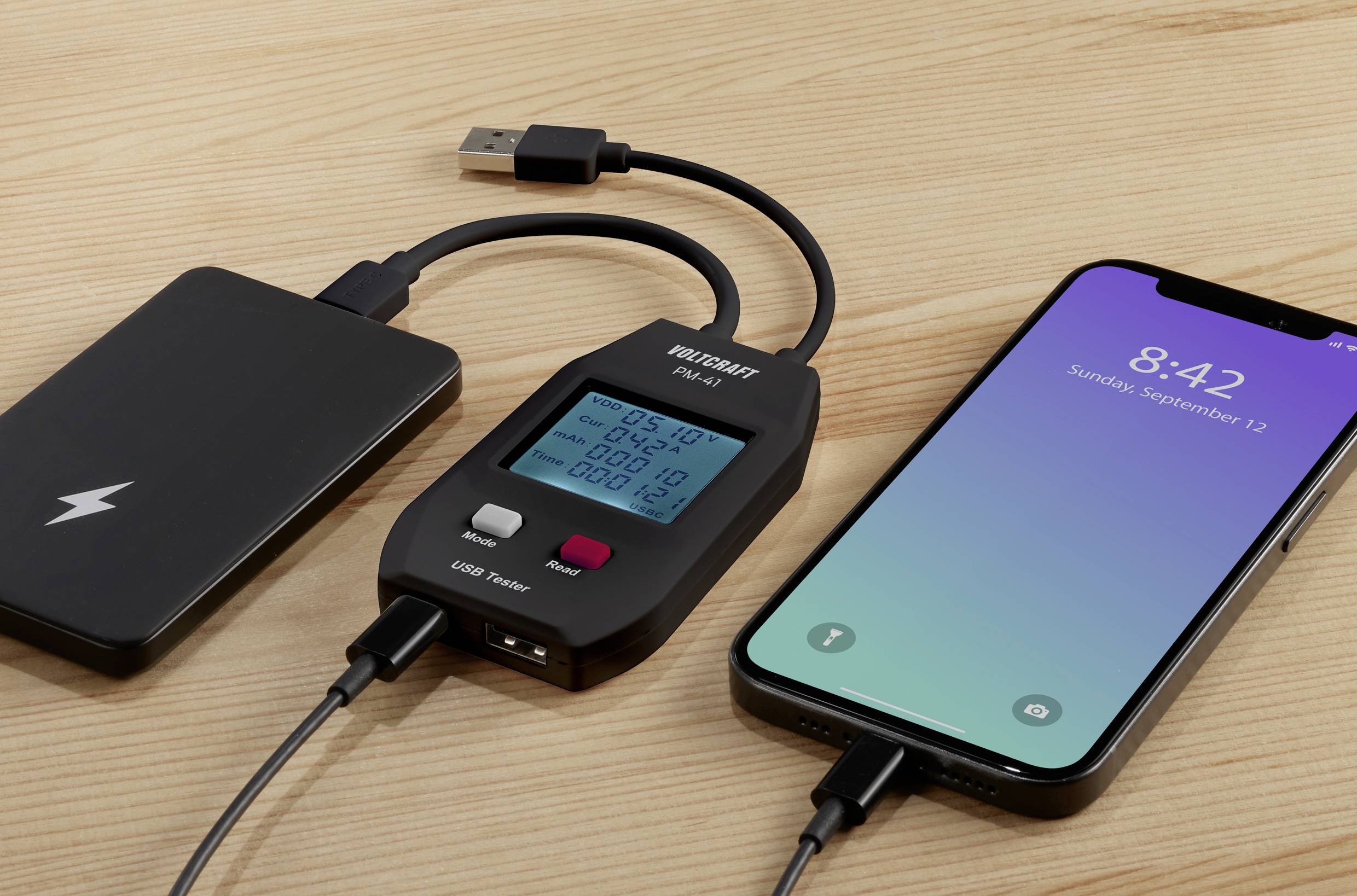 Smartphone zobrazuje čas '8:42' a je připojeno k USB měřiči výkonu, který je dále připojen k powerbance.
