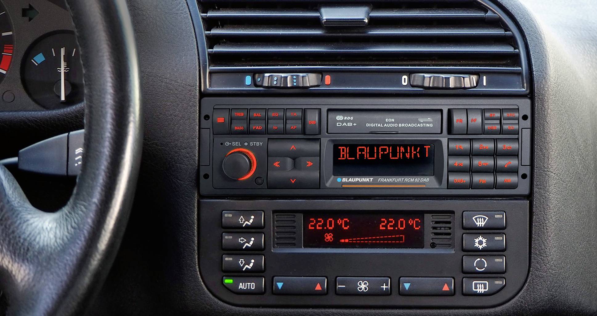 Autorádio v palubní desce automobilu zobrazuje 'BLAUPUNKT' na displeji. Regulace teploty pod ním ukazuje 22,0°C.