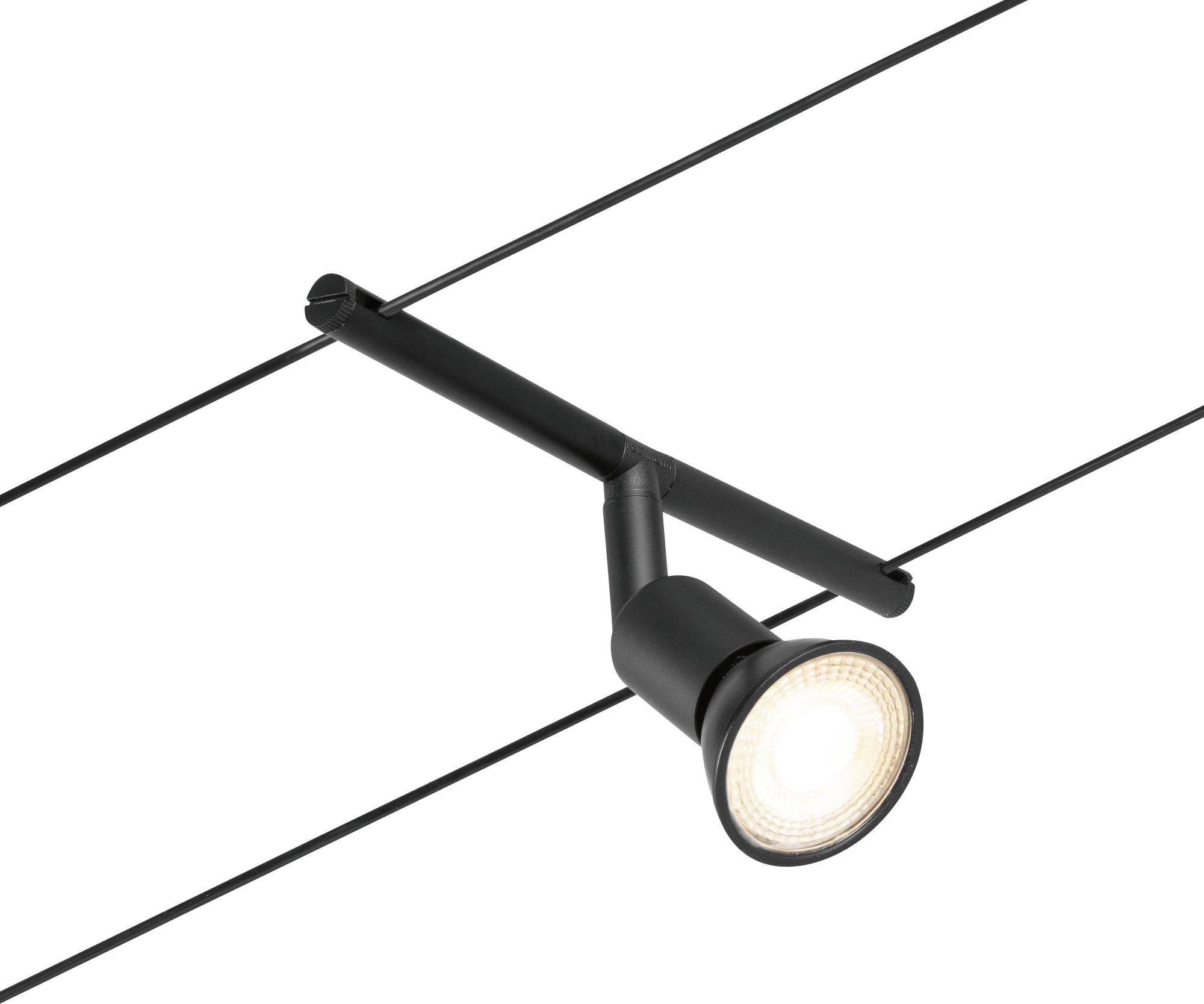 Černý stropní reflektor je namontován na dvou rovnoběžně napnutých kabelech. Lampa svítí jasně.
