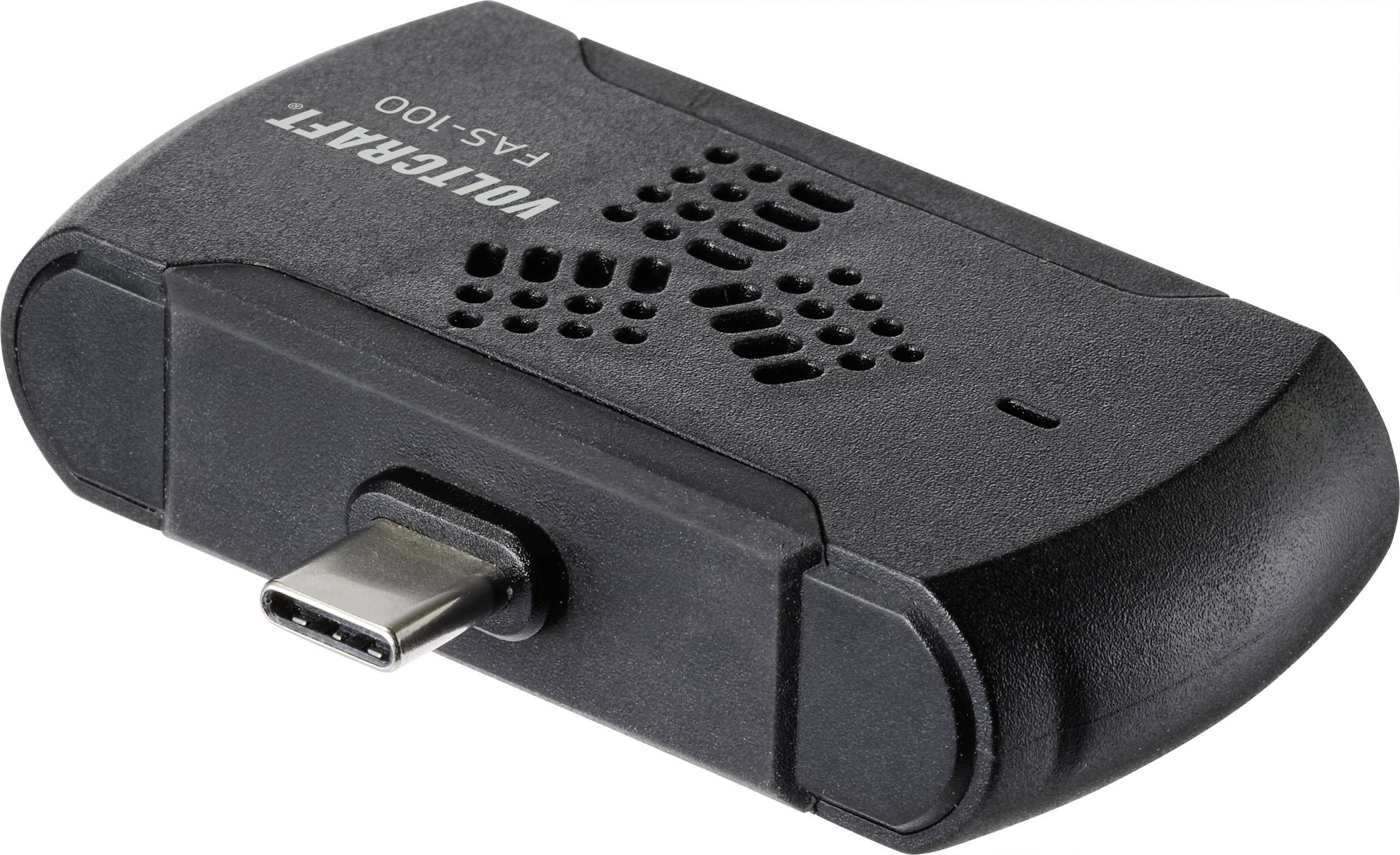 Černý adaptér s USB-C konektorem, model 'VOLCRAFT FAS-100', ležící na bílém povrchu.
