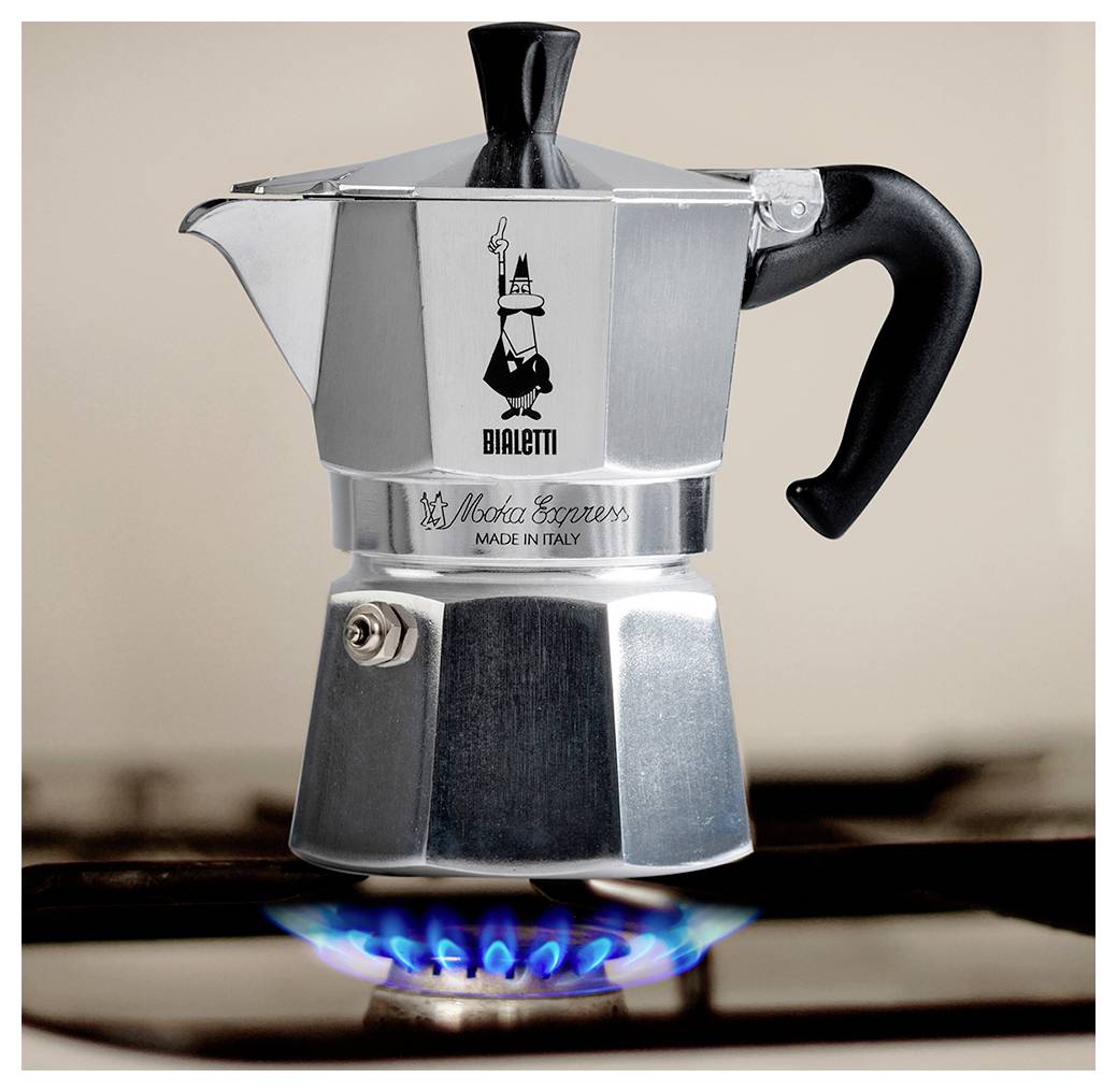 Stříbrný kávovar na espresso na zapáleném plynovém hořáku, s viditelným logem značky a textem "Vyrobeno v Itálii", umístěný v kuchyňském prostředí.