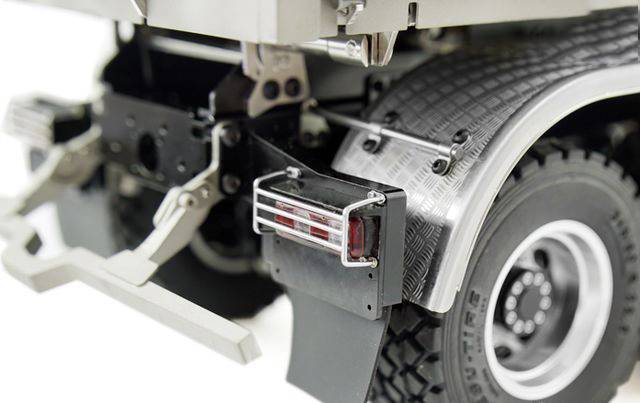 Detailní záběr zadní části modelového nákladního vozidla s precizně zobrazenými koly a zadními světly, stříbrným kovovým povrchem a strukturovaným designem.