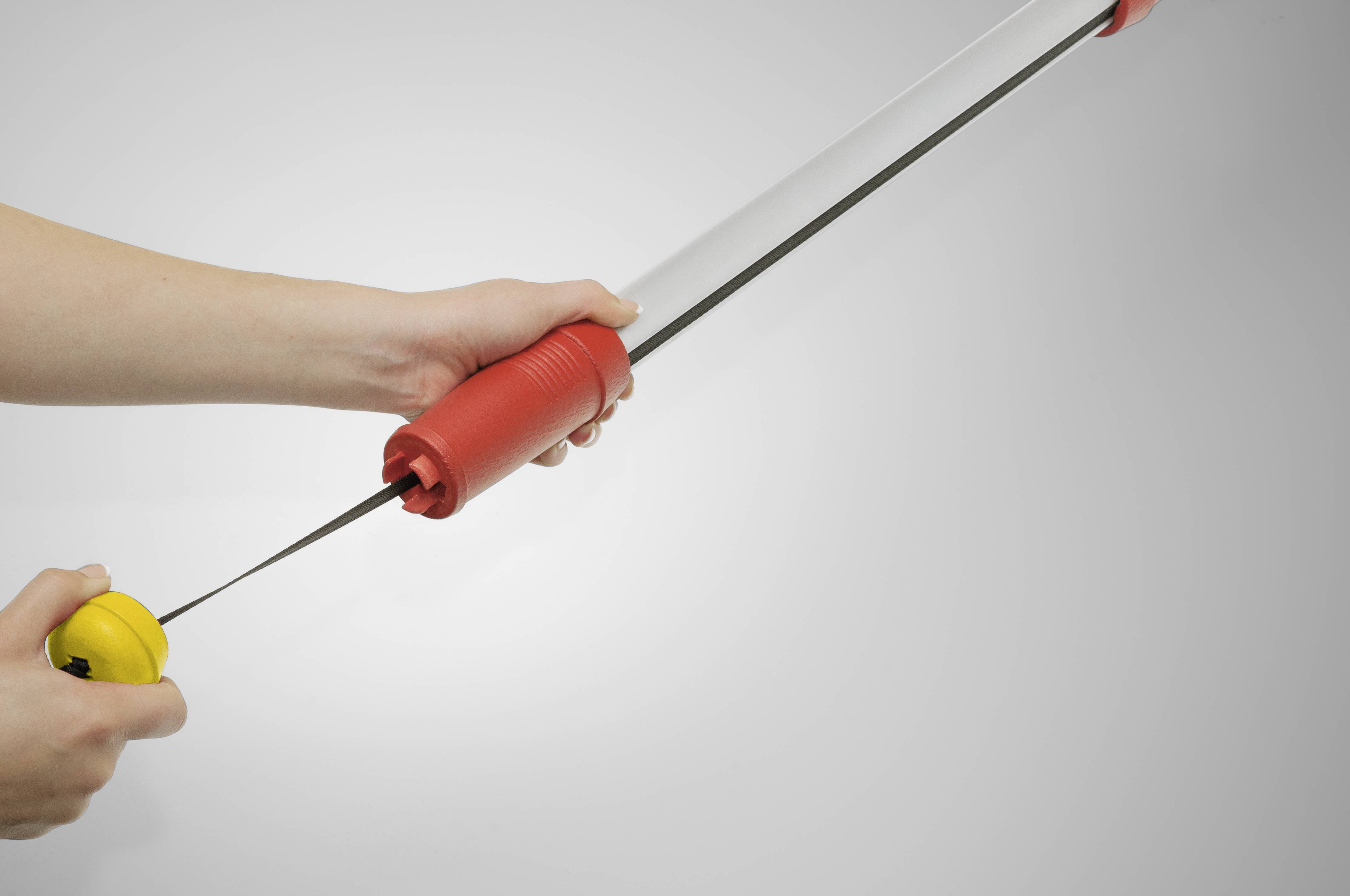 Ruce ukazují, jak je dlouhý červený a žlutý mechanismus roztahován, pravděpodobně teleskopická hůl.