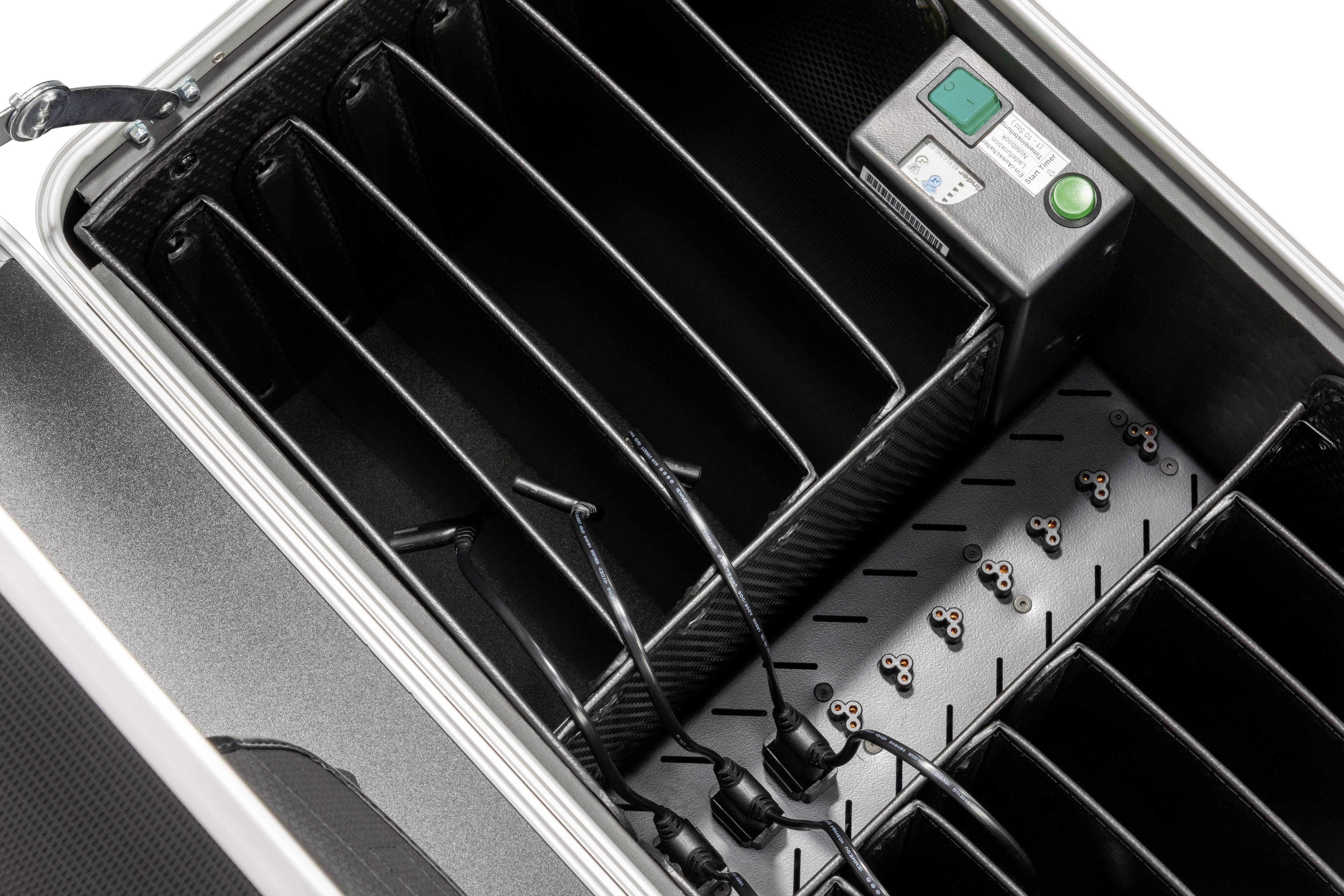 Vnitřní pohled do kufru s několika přihrádkami, kabely a ovládacím modulem s tlačítky a displeji, pravděpodobně určený pro technické vybavení.