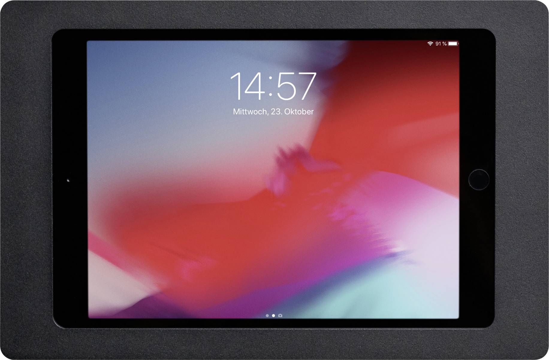 Tablet s barevným pozadím zobrazuje na obrazovce čas '14:57' a datum 'středa, 23. října'.