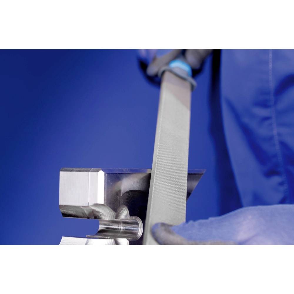 Osoba v modré pracovní kombinéze piluje kov pilníkem. Ukazuje přesnou a řemeslnou práci.