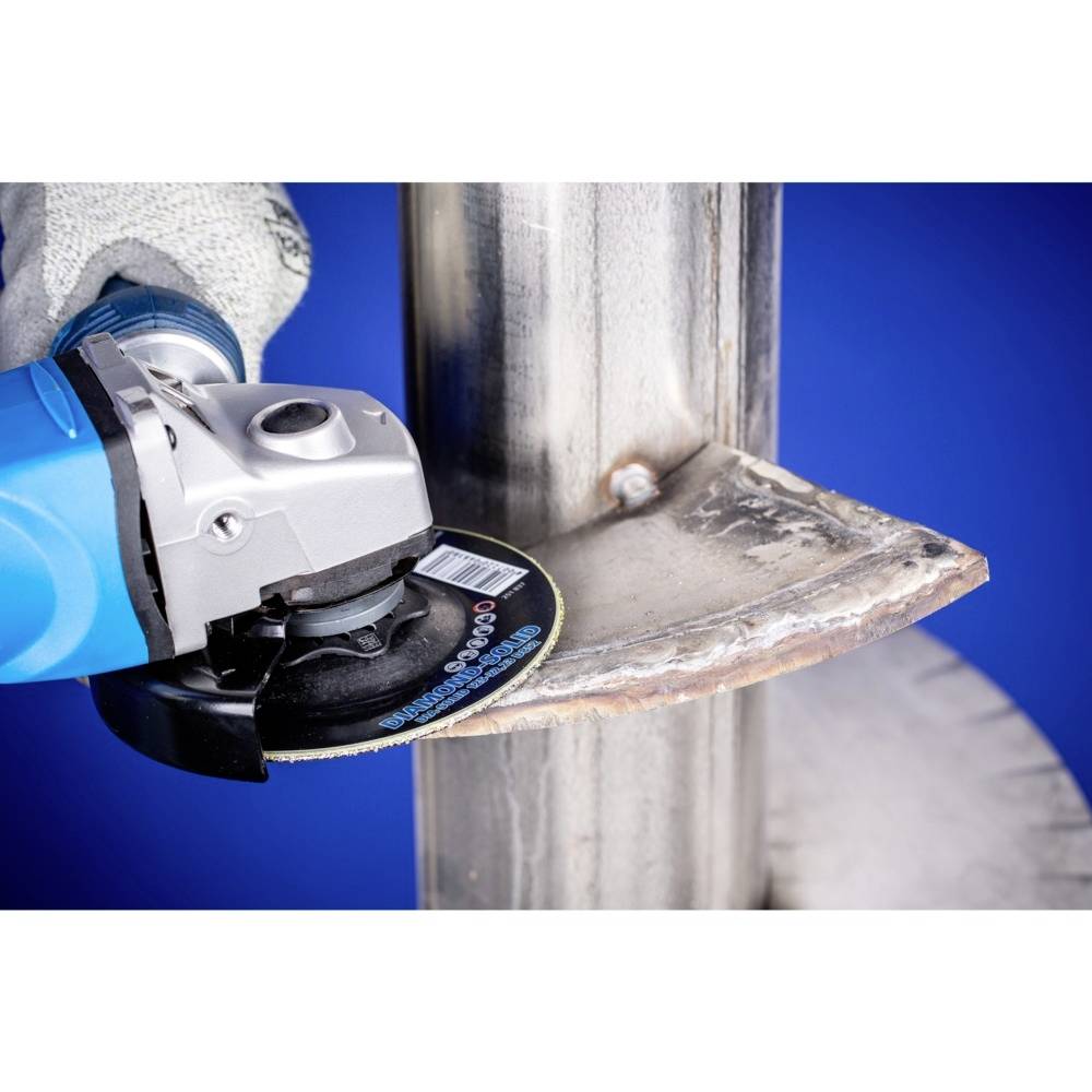 Osoba brousí kovovou trubku úhlovou bruskou. Při abrazivním řezání létají jiskry.