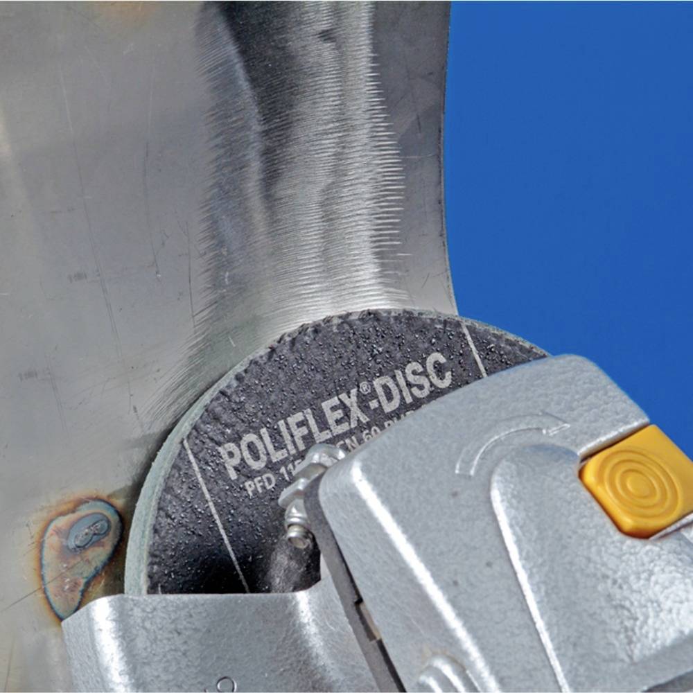 Detailní záběr brusného kotouče pracujícího na kovovém povrchu s modrým pozadím.