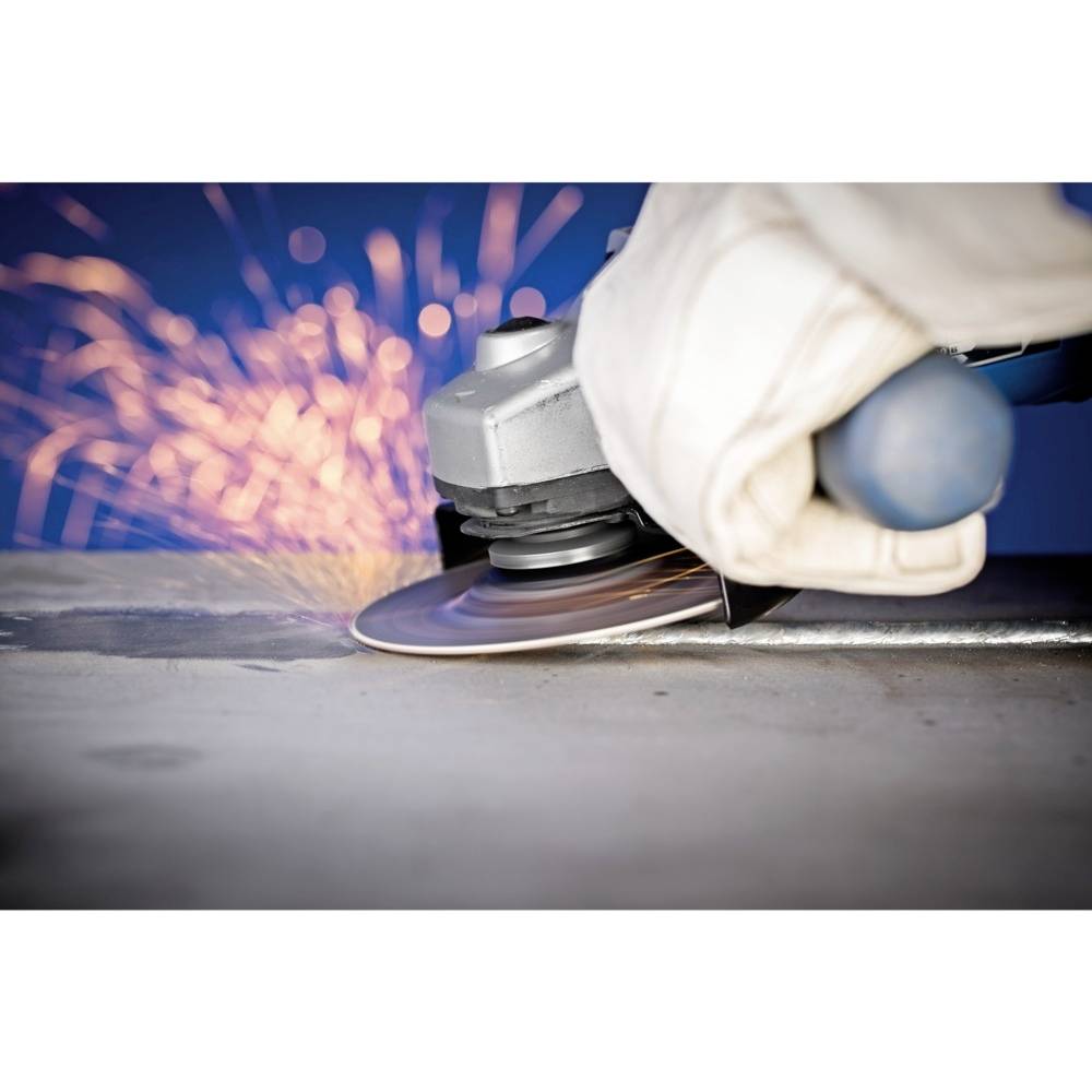 Osoba brousí kov úhlovou bruskou, přičemž kolem létají jiskry. Je oblečena v ochranném oděvu.