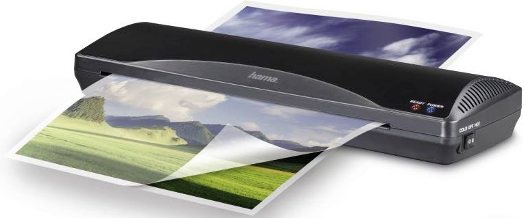 Obrázek ukazuje laminátor, který laminuje fotografii s motivem krajiny. Přístroj je černý a má vypínač.