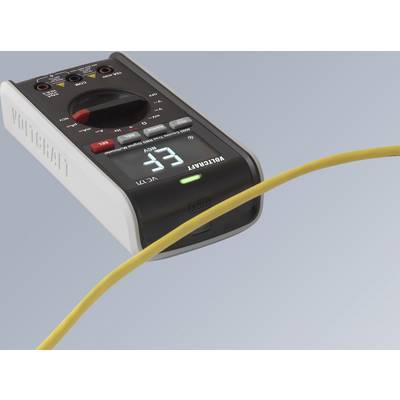 Digitální multimetr ukazuje hodnotu 3,3. Žlutý kabel je viditelný v popředí, zatímco přístroj leží na stole.