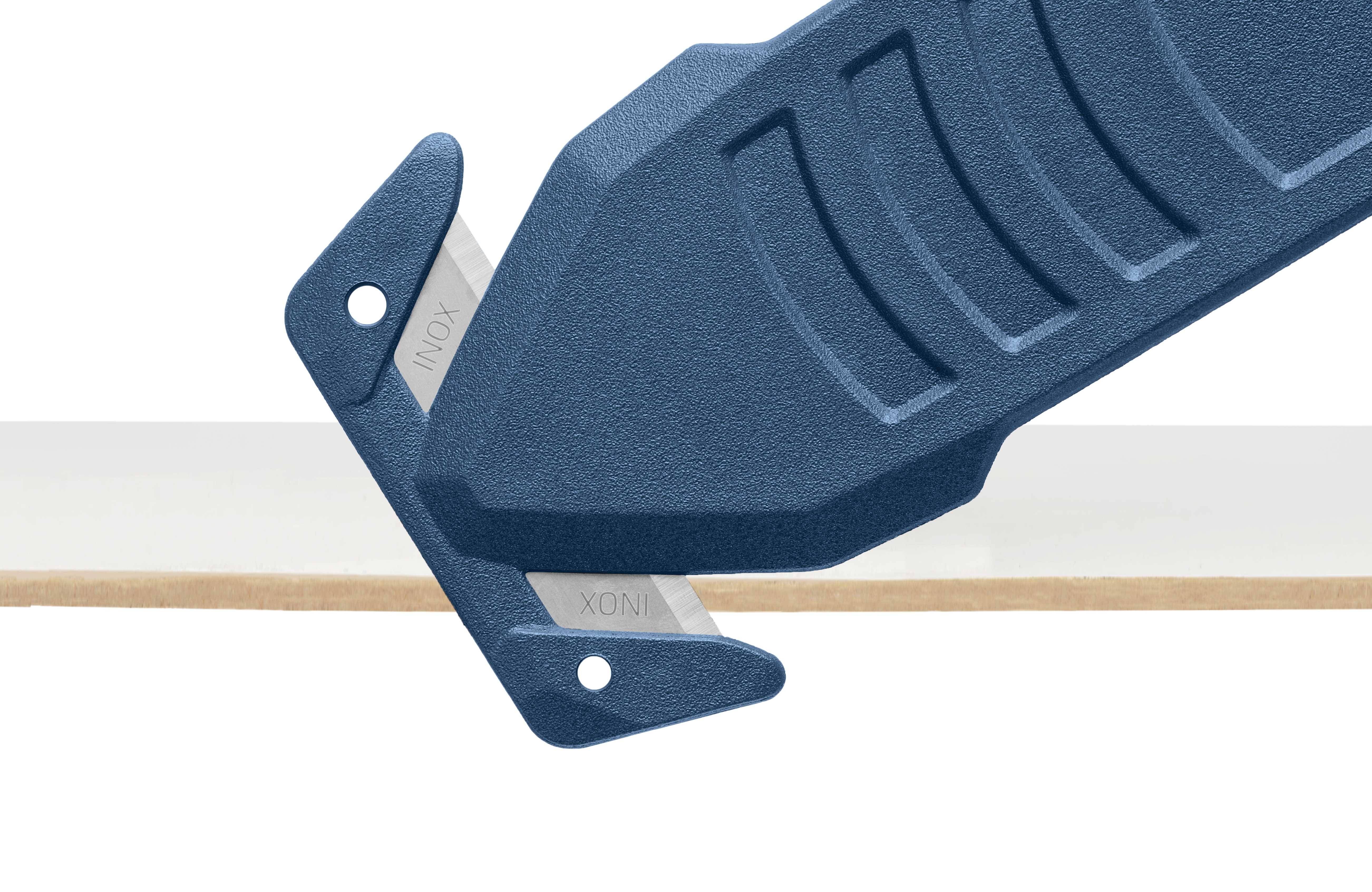 Modrý bezpečnostní řezák řeže papírový proužek. Řezák má ergonomickou rukojeť a integrované ostří.