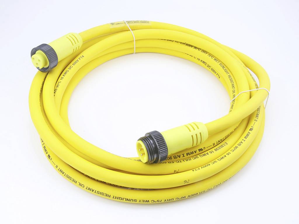 Žlutý koaxiální kabel s černými konektory, navinutý do role. Vhodný pro elektronické nebo elektrické propojení.