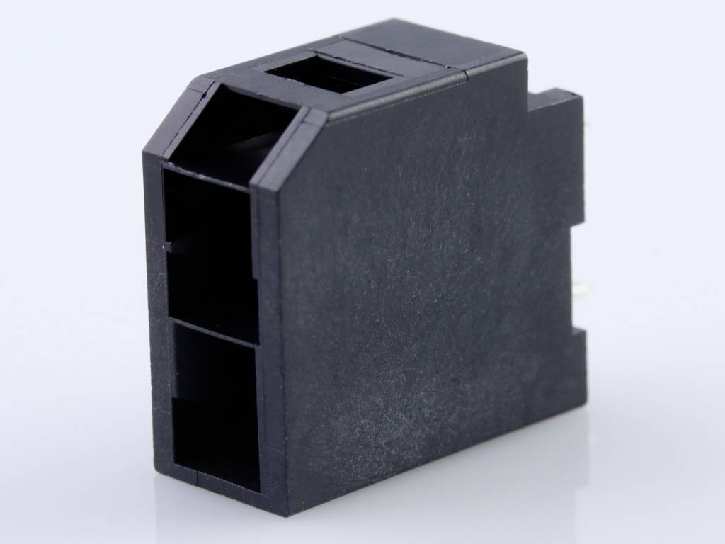 Černý plastový konektor se dvěma obdélníkovými zásuvkovými otvory, stojící na lesklém povrchu.