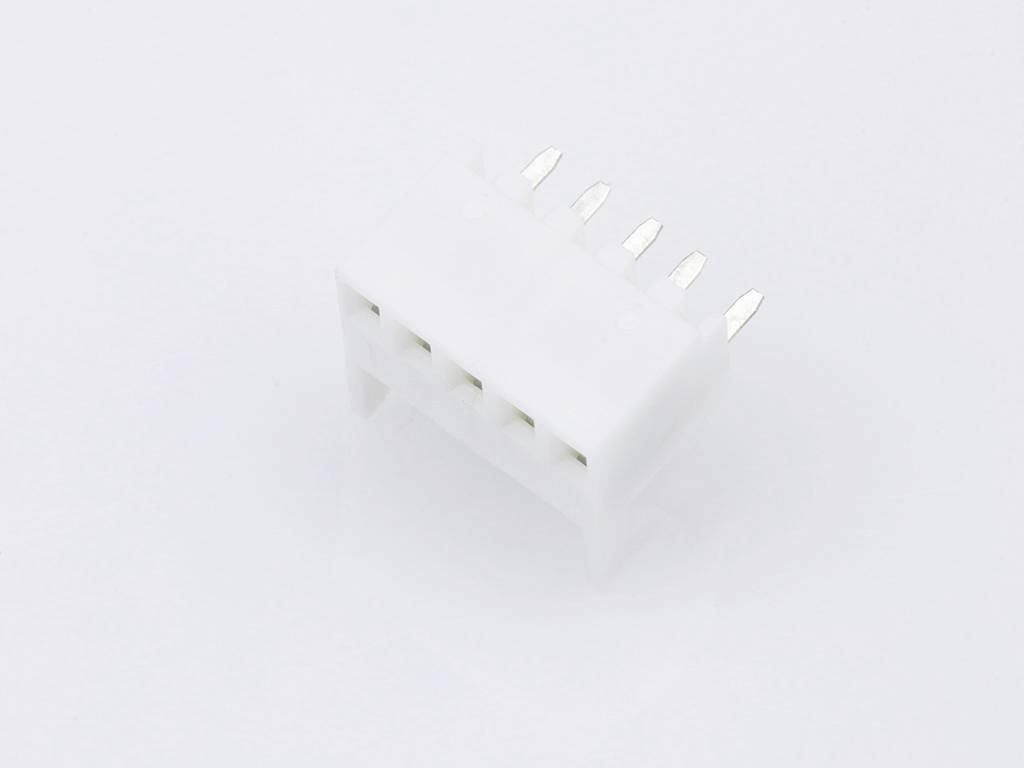 Bílý elektrický konektor s pěti kovovými kolíky, ležící na hladkém povrchu.