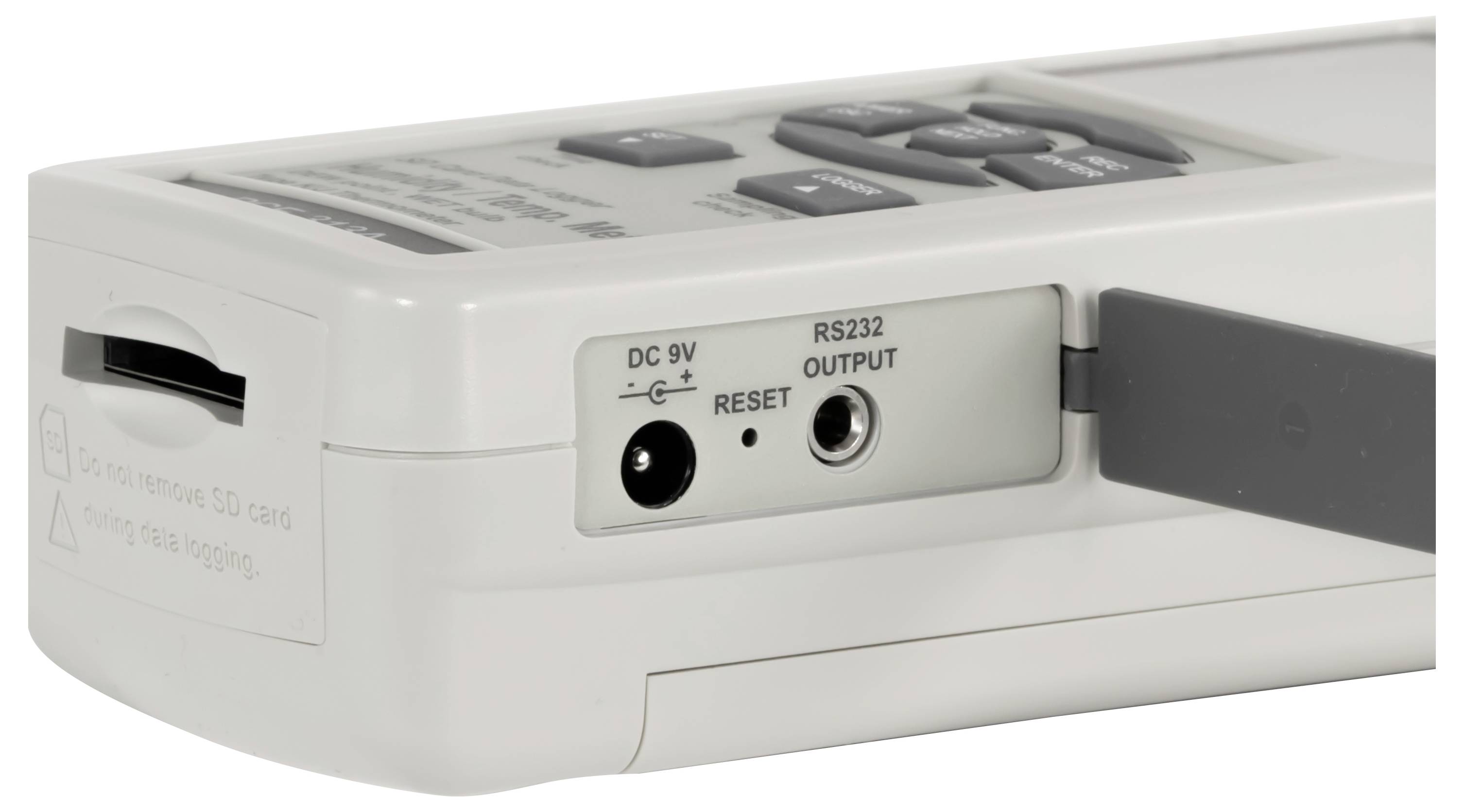 Detailní pohled na přenosné elektronické zařízení ukazující slot pro SD kartu, konektor DC 9V, otvor pro reset, výstupní port RS232 a připojený kabel.
