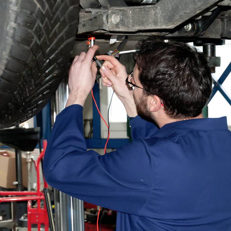 Mechanik kontroluje elektroniku diagnostickým zařízením na zvedáku v autoservisu.