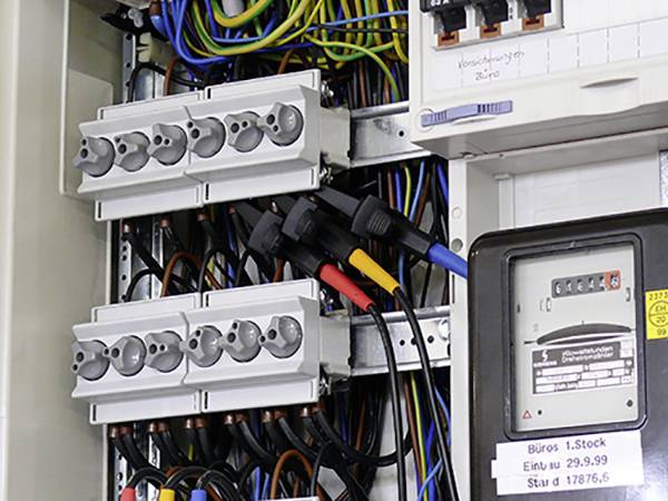 Elektrický rozvaděč s několika zásuvkami, kabely a elektroměrem. Elektroměr ukazuje spotřebu 17876,6.