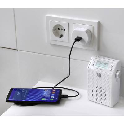 Mobilní telefon je připojen k rádiu napájenému ze zásuvky pomocí USB kabelu, přičemž rádio je samo zapojeno do elektrické zásuvky.