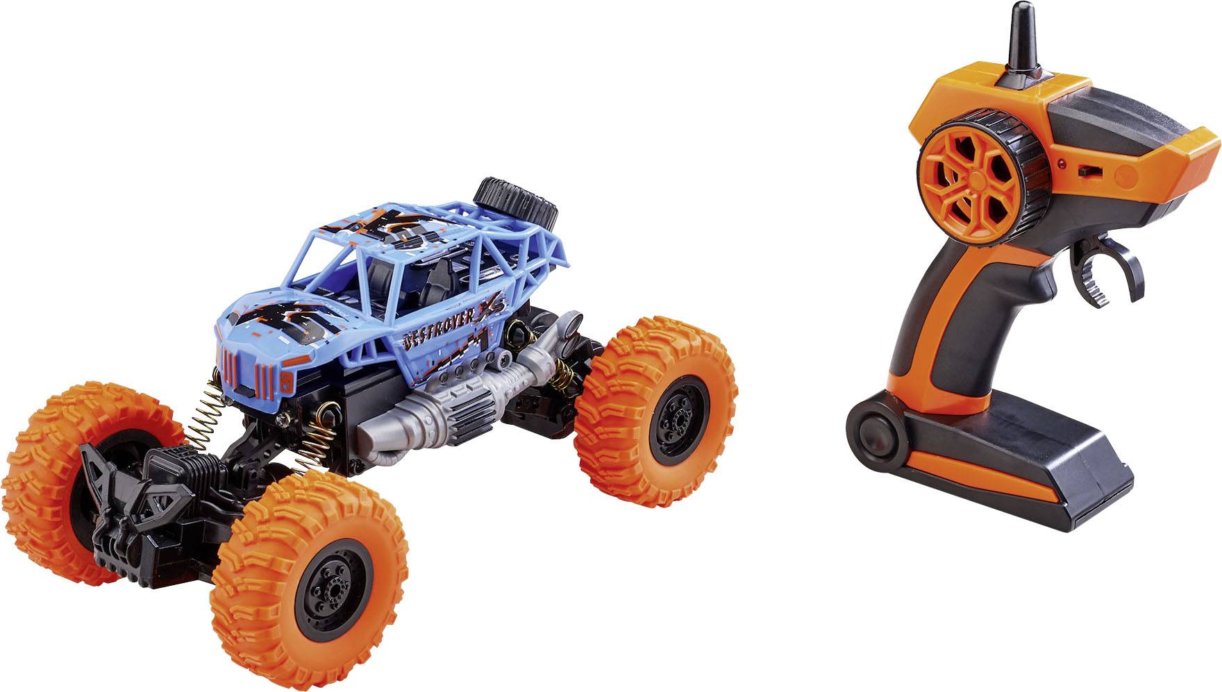 Hračkové auto ve stylu monster trucku s velkými oranžovými pneumatikami, vedle něhož leží dálkové ovládání.