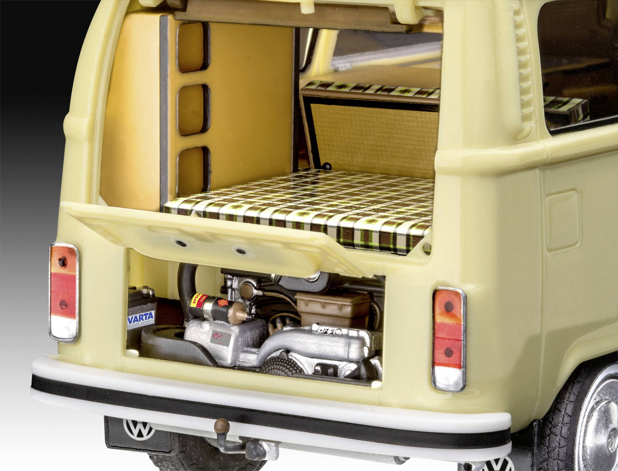 Model žlutého retro dodávkového vozu s otevřeným zadním víkem. Interiér ukazuje postel s kostkovaným vzorem a pohled na motor vzadu.