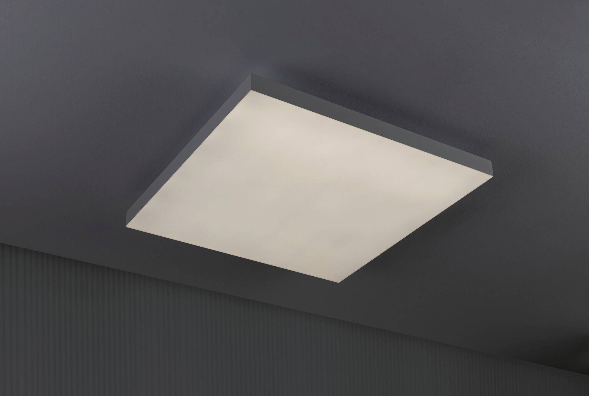 Pravoúhlé stropní svítidlo s rovnoměrným, měkkým světlem; moderní a minimalistický design v tmavém prostoru.