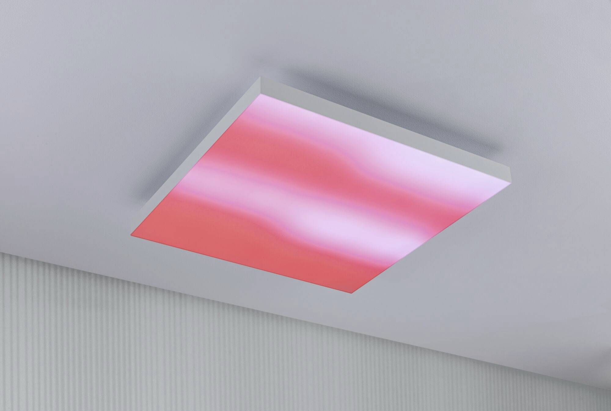 Stropní LED svítidlo v moderním prostoru, osvětlující v růžových a červených tónech, které zajišťuje stylové osvětlení a příjemnou atmosféru.